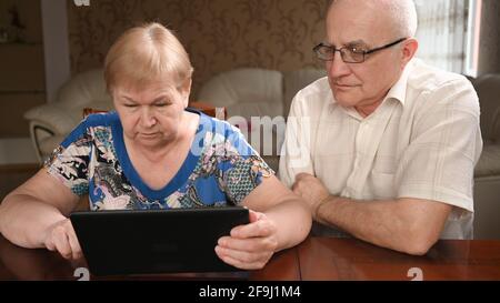 Ältere Ehepaare, die am Computer sitzen, kaufen im Internet ein. Stockfoto