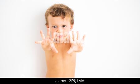 Porträt eines kaukasischen Kindes mit ausgestreckten Armen und Händen auf weißem Hintergrund. Fokus selektiv. Stockfoto