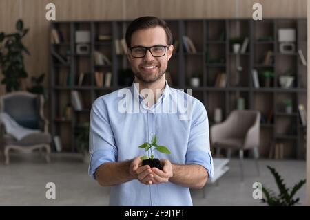 Porträt eines lächelnden Geschäftsmannes Halten Sie den Sämling in den Händen Stockfoto