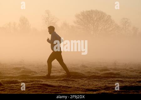 Ein Läufer im Buschy Park, während der Morgennebel verweilt, London. Bilddatum: Montag, 19. April 2021. Stockfoto