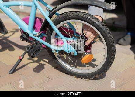 Männliche Hände Pumpen das Rad auf einem Kinderfahrrad hoch. Pumpen von Luft in ein Fahrrad-Rad. Nahaufnahme Stockfoto