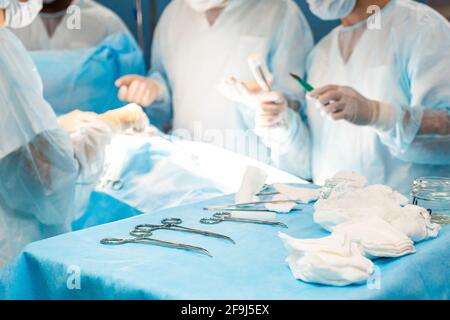 Ein internationales Ärzteteam führt eine komplexe chirurgische Operation an einem unter Anästhesie stehenden Patienten durch. Moderner Operationssaal und erfahrene Chirurgen Stockfoto