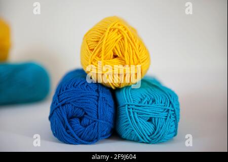 Zitronengelbe, türkisfarbene und königsblaue Baumwollgarne in Knäuel zum Stricken, Nadelarbeiten oder Häkeln, schöne Auswahl an Baumwollkugeln Stockfoto