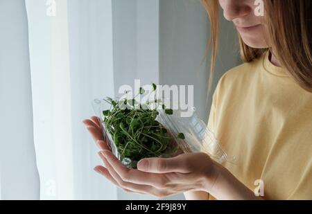 Frau, die einen Plastikbehälter mit essbaren Brokkoli-Sprossen hält. Microgreens-Konzept Stockfoto