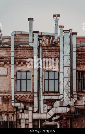 Aluminiumlüftungsrohre außerhalb des alten Industriegebäudes der Fabrik. Umweltverschmutzung und Ökologie, vertikaler Vintage-Hintergrund Stockfoto