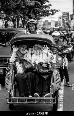 Zwei Lächelnde Indonesische Frauen, Die Mit Dem Motorrad-Taxi In Yogyakarta, Indonesien Reisen. Stockfoto