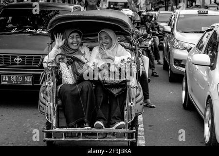 Zwei Lächelnde Indonesische Frauen, Die Mit Dem Motorrad-Taxi In Yogyakarta, Indonesien Reisen. Stockfoto