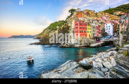 Bunte Häuser auf einem Felsen über dem Mittelmeer in Riomaggiore, einem der fünf Dörfer an der Küste von Cinque Terre, Ligurien, Italien Stockfoto