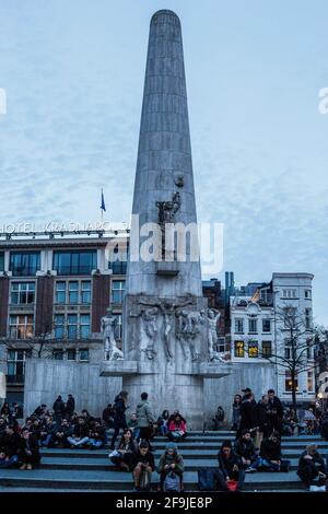 Amsterdam, Niederlande - 11. März 2017: Blick auf Menschen, die vor einem Nationaldenkmal auf dem Dam-Platz im Stadtzentrum sitzen Stockfoto