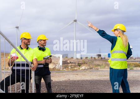 Zwei qualifizierte Arbeiter hören den Erklärungen der Ingenieurin Frau über die Nuancen der Arbeit zu. Erneuerbare Energien und professionelles Arbeitskonzept. Stockfoto