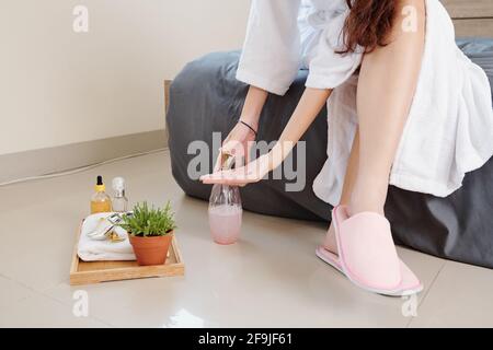 Beschnittenes Bild einer jungen Frau, die parfümierte Feuchtigkeitscreme auf sie anwendet Körper nach dem Baden Stockfoto
