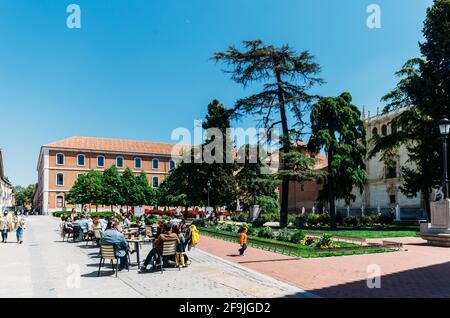 Die Menschen entspannen sich auf einer Terrasse mit Blick auf die Fassade der Universität von Alcala aus dem 16. Jahrhundert, Spanien Stockfoto