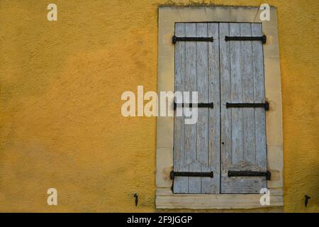 Ländliche Hausfassade im Provençal-Stil mit grauen Holzfensterläden an einer ockerfarbenen Wand im malerischen Dorf Lourmarin Vaucluse, Provence Frankreich. Stockfoto