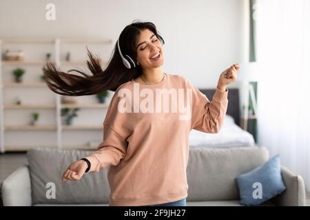 Junge Frau, die tanzt und ein schnurloses Headset trägt Stockfoto