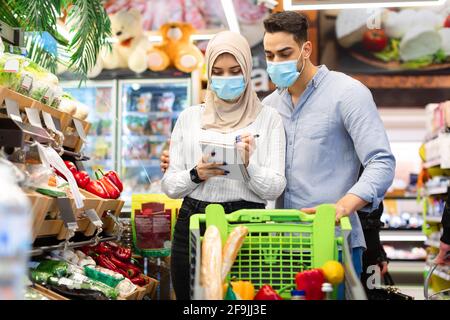 Muslimisches Paar Nimmt Notizen In Lebensmitteleinkaufsliste Im Supermarkt Stockfoto