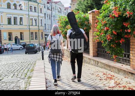 Kreative Teenager Kerl und Mädchen, die mit Gitarre im Fall gehen, Rückansicht Stockfoto