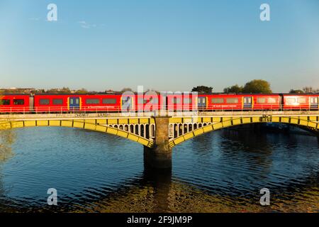 South Western Railway Zug, der die Themse bei Richmond überquert, von der Twickenham Brücke bei Sonnenuntergang mit blauem Himmel und Sonne / blauem Himmel und sonnigem Himmel gesehen. Richmond upon Thames. Vereinigtes Königreich (123) Stockfoto