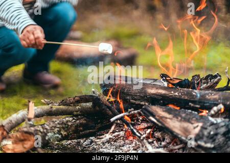 Auf einem Stock wird über einem Campingfeuer ein Marschall geröstet Stockfoto