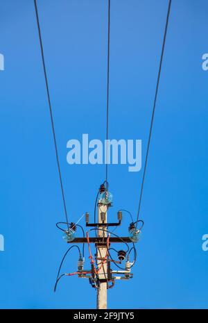 Elektrizitätskonzept, Oberseite einer Betonsäule mit Hochspannungsdrähten. Nahaufnahme gegen den blauen Himmel. Stromleitung in der Nähe der Hochspannungstransformatorstation. Stockfoto