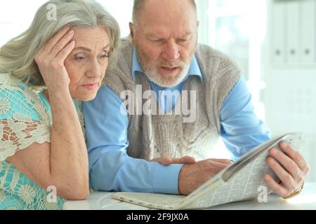 Seniorenpaar sitzt am Tisch und liest Zeitung Stockfoto