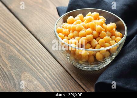 Gekochte Kichererbsen in einer Glasschüssel auf rustikalem Holztisch mit blauem Tuch in der Nähe, Nahaufnahme, Kopierraum, fastennast der fastenzeit, veganes Proteinmeal-Konzept Stockfoto