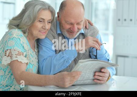 Seniorenpaar sitzt am Tisch und liest Zeitung Stockfoto