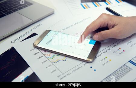 Nahaufnahme der Hände eines Geschäftsmannes mithilfe der Berechnung auf dem Smartphone am Schreibtisch. Stockfoto