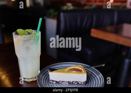 Karamellkuchen Dessert auf Teller und eisgekühlter grüner Cocktail mit Minze auf dem Tisch im Café Stockfoto