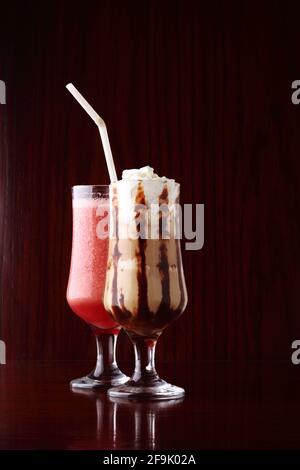 Erdbeer-Smoothie und Affogato, ein italienisches Espresso-Getränk auf Kaffeebasis mit einer Kugel Vanilleeis und Schlagsahne über Holzbackgro Stockfoto