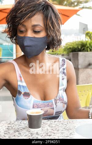Nahaufnahme des Gesichts einer afroabhängigen Frau mit kurzen Haaren, im Freien in legerer Kleidung und geschützt mit Maske, Schönheit und Modernität Stockfoto