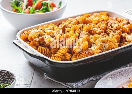 Gebackene Pasta mit Huhn und Käse in der Ofenform, grauer Hintergrund. Italienisches Küchenkonzept. Stockfoto