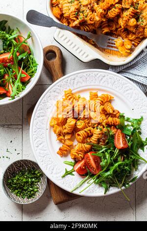 Gebackene Pasta mit Huhn und Käse auf weißem Teller, grauer Hintergrund. Italienisches Küchenkonzept. Stockfoto