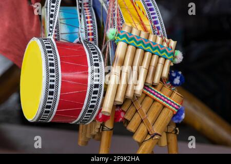 Bunte und handgemachte Musikinstrumente, die in einem Geschäft aufgehängt wurden, Details der Trommel und der Panflöte, Nahaufnahme der Objekte