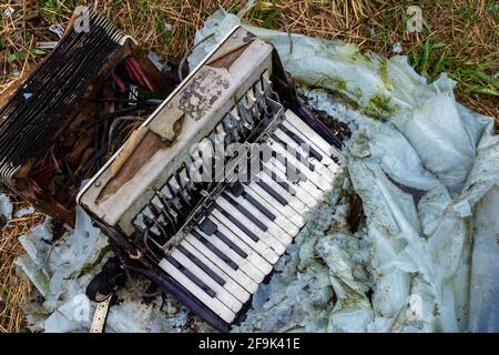 Alte, beschädigte Ziehharmonika im Hof aufgegeben. Hergestellt bei schlechten Lichtverhältnissen Stockfoto