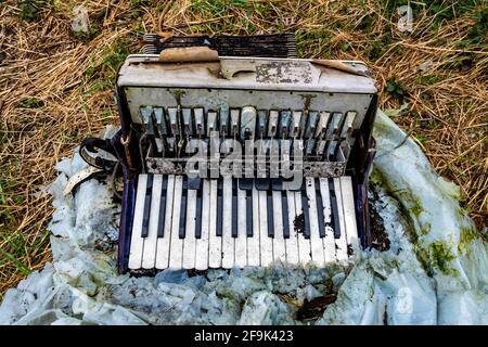 Alte, beschädigte Ziehharmonika im Hof aufgegeben. Hergestellt bei schlechten Lichtverhältnissen Stockfoto