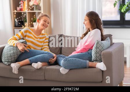 Glückliche Teenager-Mädchen reden auf dem Sofa zu Hause Stockfoto