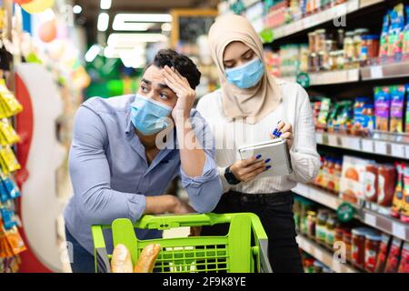 Unglückliches Muslimisches Paar, Das Preise Berechnet, Lebensmittel Einkaufen Im Supermarkt Stockfoto