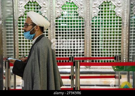 Teheran, Iran. April 2021. Ein iranischer Geistlicher, der eine schützende Gesichtsmaske trägt, geht in die Nähe des Schreines von Schah Abdol-Azim.der Schrein von Schah Abdol-Azim ist mit einem roten Band geschützt, um Besucher daran zu hindern, ihn und den COVID-19-Ausbruch zu berühren. (Foto: Sobhan Farajvan/Pacific Press/Sipa USA) Quelle: SIPA USA/Alamy Live News Stockfoto