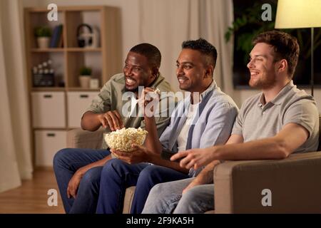 Männliche Freunde mit Popcorn, die zu Hause Fernsehen Stockfoto