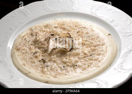 Cremiges Käse-Risotto mit Trüffelscheiben, in weißer Schale, aus nächster Nähe Stockfoto