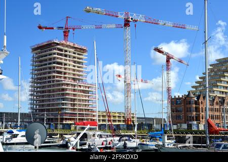 Ostend, Westflandern, Belgien - 17. April 2021: Wohnungsbau im Bau. Vor dem Schiff dockten Segelschiffe in Mercator Marina Oostende an. Stockfoto