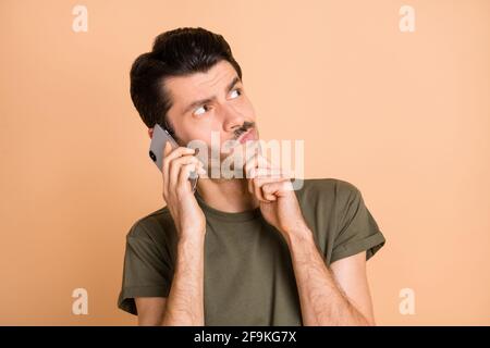 Foto von jungen nachdenklichen gesinnten ernsten Mann aussehen copyspace Gespräch Am Telefon denken isoliert auf beigefarbenem Hintergrund Stockfoto