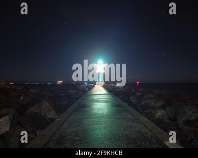 Westmole Leuchtturm, leuchtendes Wellenbrecherlicht an der Mündung eines Hafens. Novembernacht, Warnemünde Strand, Deutschland Stockfoto