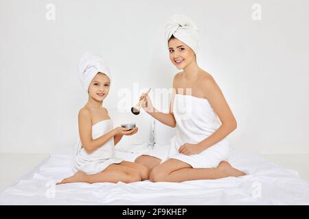 Mutter und kleine Tochter machen Make-up im Schlafzimmer Stockfoto