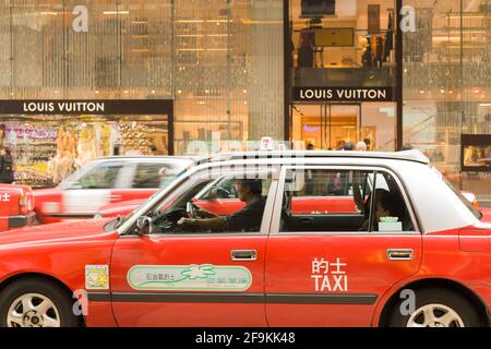 Hongkong, Central District, China, Asien - traditionelle rote Taxis vor einem Louis Vuitton Geschäft im Central District Hong Kong. Stockfoto