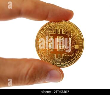 Eine Bitcoin-Münze zwischen den Fingern. Motiv auf weißem Hintergrund isoliert. Stockfoto