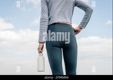 Rückansicht einer sportlichen Frau mit einer Flasche Wasser. Nahaufnahme. Stockfoto