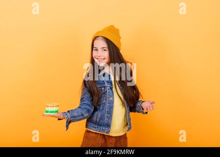 Ein Mädchen in einem mehrfarbigen Hemd hält ein mehrfarbiges, slinky Spielzeug In ihren Händen Stockfoto