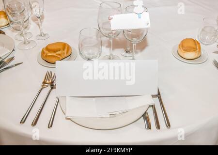 Leere Karte mit Platz zum Kopieren, die während einer Feier auf einem Teller auf einem Restauranttisch platziert wird. Stockfoto