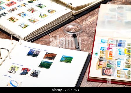 Briefmarkenalben voll gebrauchter britischer Briefmarken aufgelegt Eine rustikale Holztischplatte Stockfoto